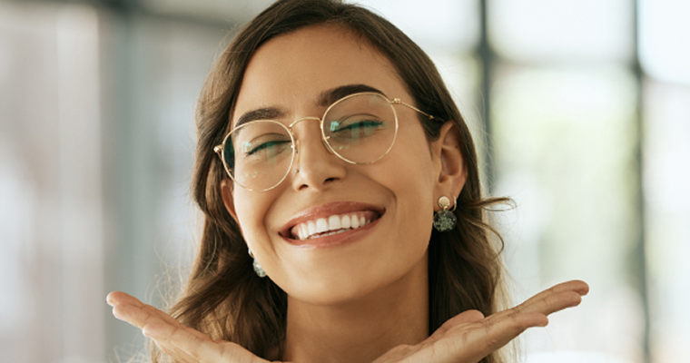 Smiling woman with glasses framing her face with her hands